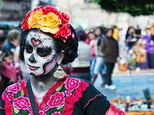 一个人戴着天死糖的骷髅妆, a flower headband, and traditional spanish dress.